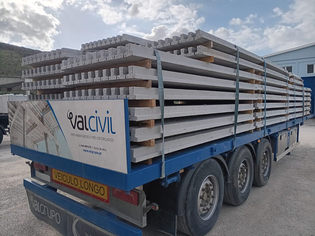 Camião carregado com vigotas pré-fabricadas de betão para transporte.